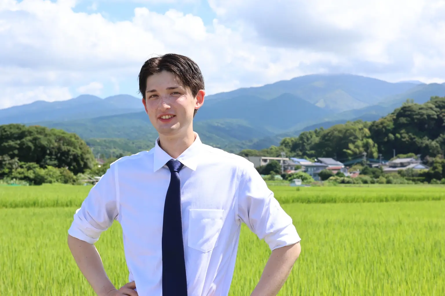 裾野の田園と山を背景に立つ星野ひろみ
